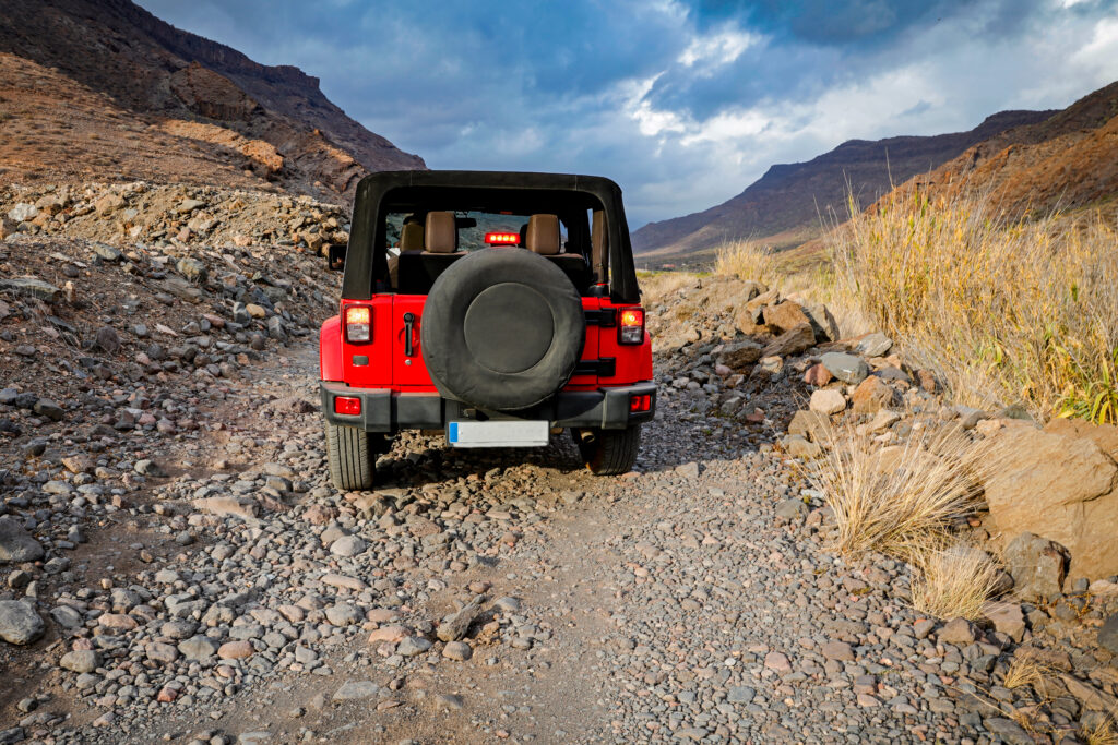 A red jeep on sandy beach and beuatiful blue sunny sky view in summer time.